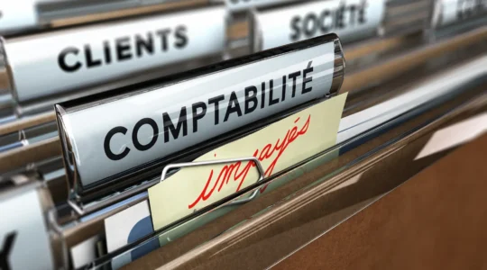 Responsable recouvrement consultant un planning mural structuré des étapes de relance dans un bureau de PME française